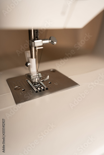 Foto close-up of a sewing machine needle and presser foot in warm beige studio lighti