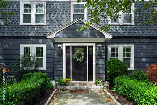 Front entrance of a traditional gray house with a green door wreath in Brookline Massachusetts
