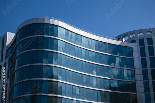 Modern building facade with curved blue glass panels. Office building exterior with unique appearance on blue sky