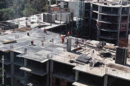 Large residential building high-rise construction site with several workers on the roof of a building