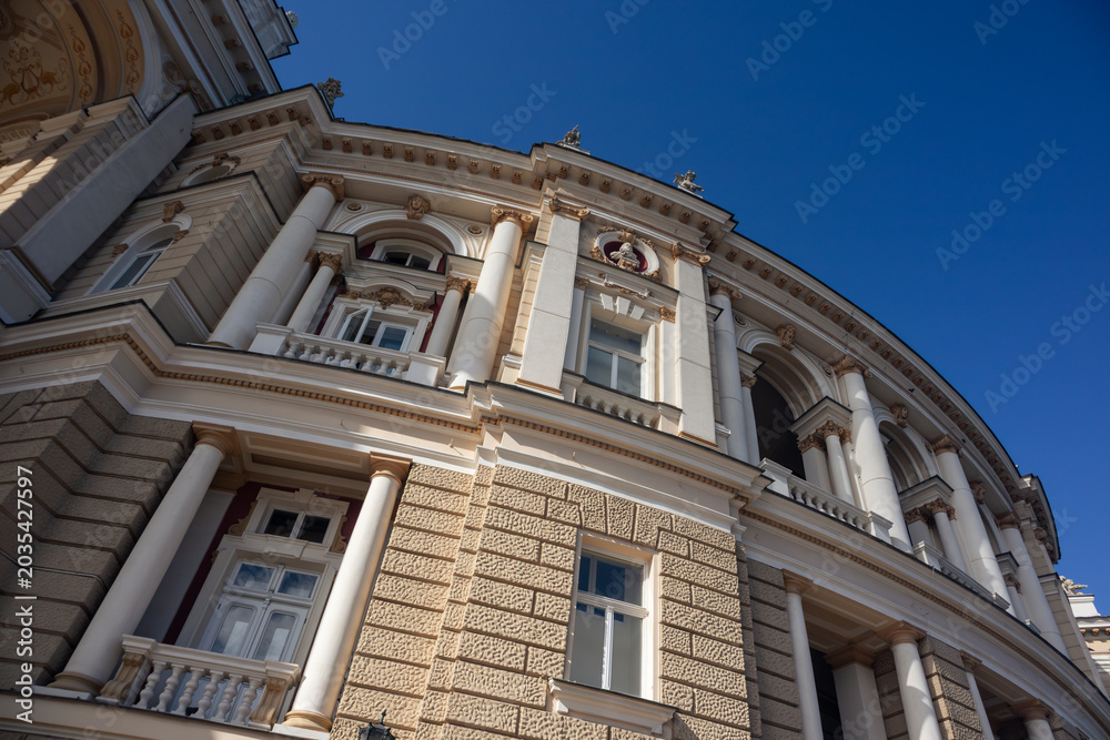 Obraz premium Elegant curved architectural theater facade with columns and windows. Detailed stonework against clear blue sky