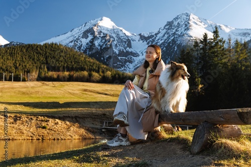 Woman with Collie Dog Sitting on Log Bench by Mountain Lake in Tatra Slovakia