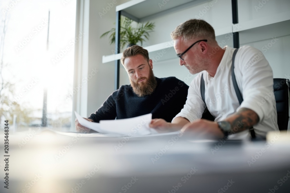 Fototapeta premium The Two Men Reviewing Blueprints at a Modern Office Table