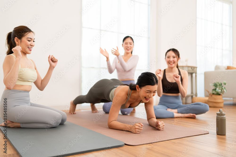 Obraz premium Women practice yoga and fitness in a bright studio during a group workout session while supporting each other
