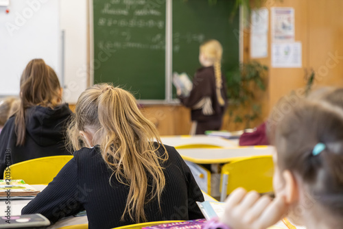 Foto Elementary school children sitting at desks while a student recites a lesson at