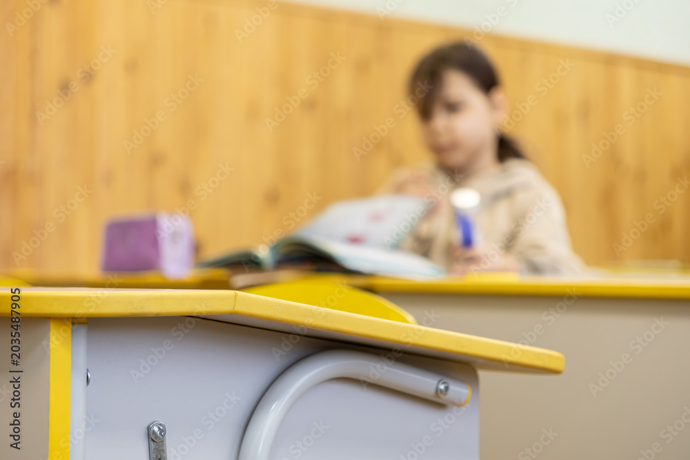 Obraz premium Schoolchild studying in a bright classroom at a desk, representing primary education, academic progress, focus on learning, knowledge acquisition and childhood development concepts