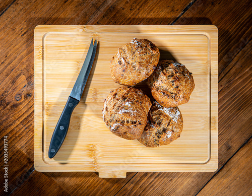 Bild auf Leinwand Four classic farm country bread buns on a wooden chopping board next to a cheese knife