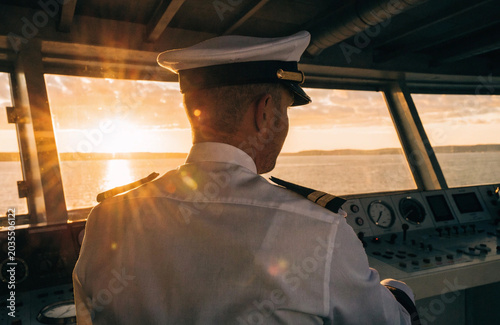 Ship Captain Standing on Wheelhouse Bridge Overlooking Sunset Sea Navigation and Maritime Control