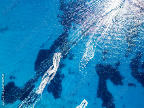 Aerial View of Speedboats and Wakes Crossing Clear Turquoise Ocean Water on a Sunny Day
