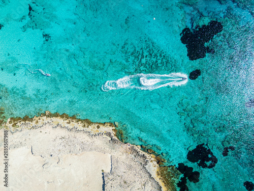 Aerial View of Turquoise Sea and Speedboat Skimming Along Rocky Coastline on Sunny Day, Cyprus, Ayia Napa