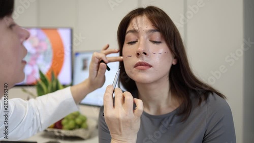 Young woman getting facial correction markings during cosmetic consultation reflecting modern obsession with perfect beauty standards and aesthetic transformation trends