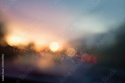 Sunset reflecting on wet glass creating bokeh effect during twilight