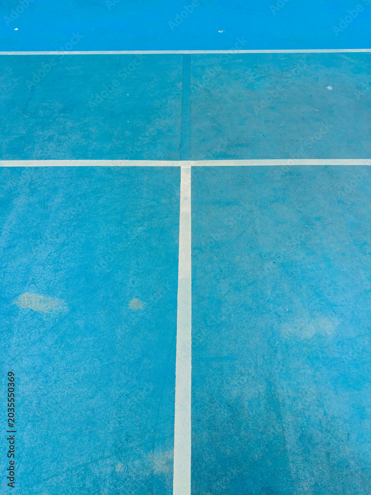 Fototapeta premium Blue tennis court with white lines showing wear and tear from use with marks and dirt visible on surface
