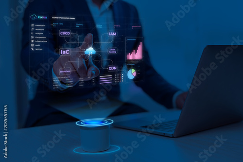 Person analyzing data on futuristic digital dashboard of cloud operations control panel with glowing blue interface in dark workspace