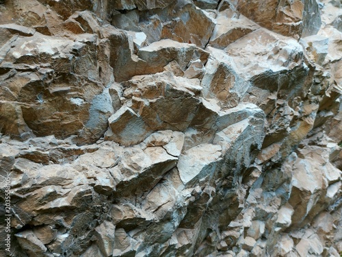 Fotografie Layered rock face texture with sharp diagonal fractures and detailed stone surfa