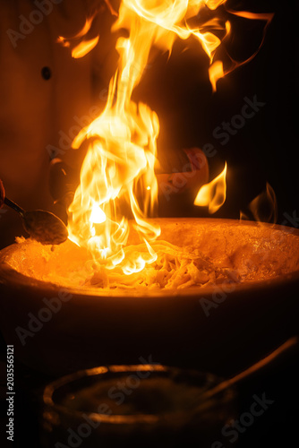 Pasta preparation with chef using torch at restaurant during evening service