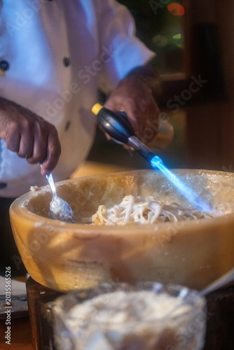 Pasta preparation with chef using torch at restaurant during evening service