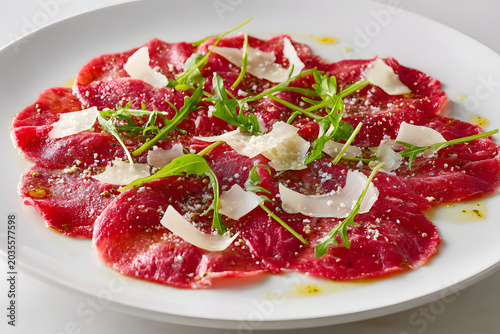 Classic Italian Beef Carpaccio Served on a Full Plate with Fresh Herbs and Parmesan Cheese