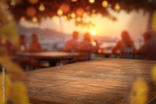 Wooden table with clean copy space for product placement and relaxing summer atmosphere with blurred summer picnic background.