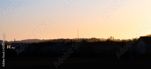 Φωτογραφία Wide suburban skyline with rooftops under warm fading sunset horizon glow