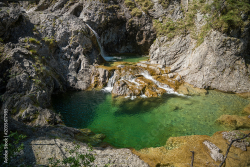 Photos Emerald Mountain Pool and Small Waterfall Flowing Through Rocky Alpine Gorge in
