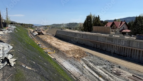 Construction of railway line LK104 with advanced ground stabilization and engineering structures. Geotechnical works including pile walls, soil reinforcement, ground nails, and slope protection system