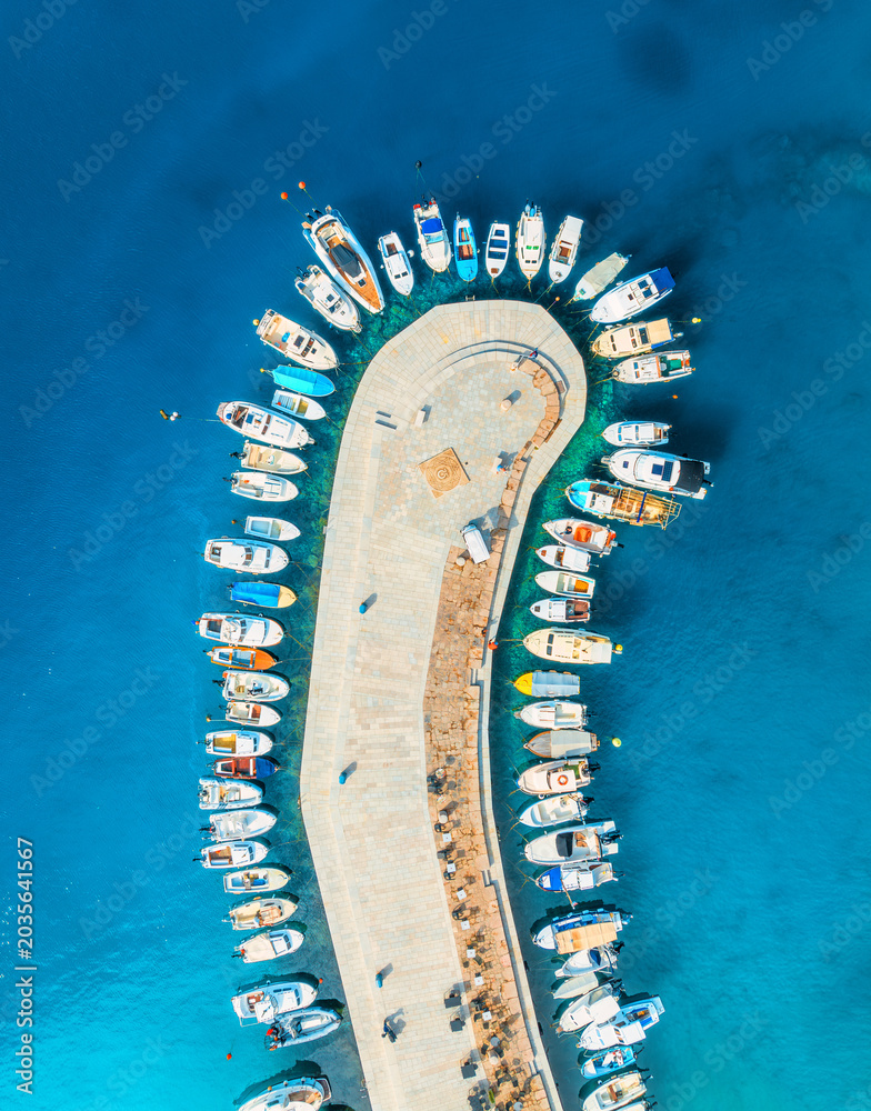 Obraz premium Aerial view of boats and luxury yachts in dock at sunset in summer in Krk island, Croatia. Colorful landscape with sailboats and motorboats in sea bay, jetty, clear blue sea. Top down view of harbor