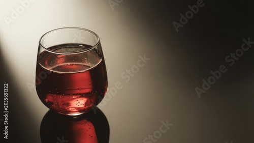 Red wine in a stemless wine glass on a reflective surface
