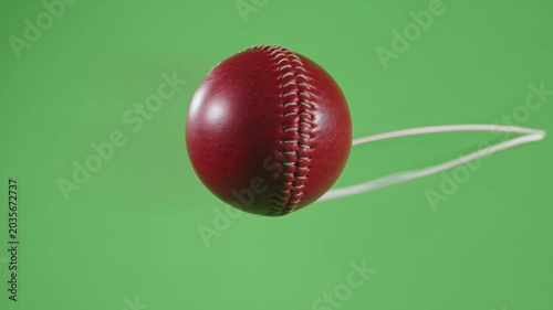 Red cricket ball floating on green background