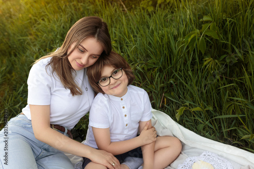 Mother and Son Sitting in Tall Grass at Sunset