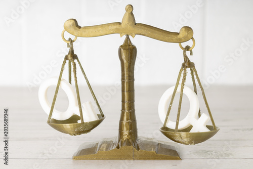 Concept of equity and equality between men and women, scale, on wooden table 