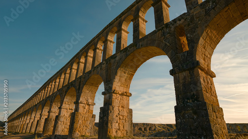 Ancient stone aqueduct architecture at sunset, concept of engineering and history.