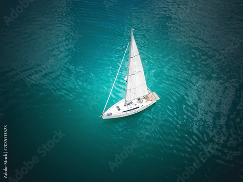 Aerial view of a white luxury sailing yacht cruising on turquoise sea water