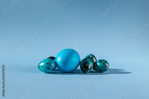 A beautiful still life in blue tones. Dyed eggs of different sizes on a light background.