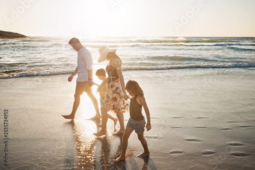 Holding hands, walking and children with parents on beach for vacation, getaway or weekend trip with bonding. Love, outdoor and family for connection by ocean together on seaside holiday with fun.