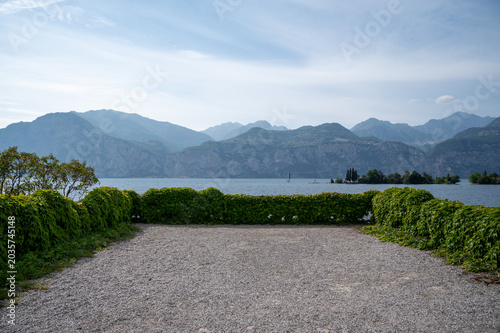 Scenic Lake Garda panorama with gravel foreground and mountain range.