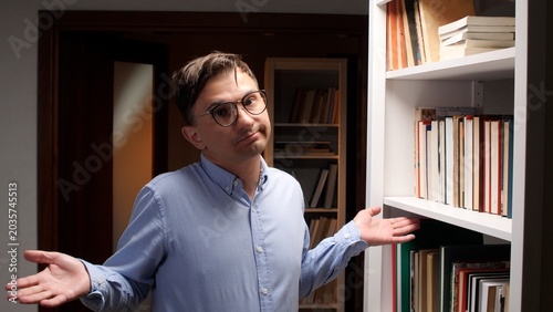 Tableau sur toile Young man in glasses shrugging with open hands, showing a puzzled or uncertain e
