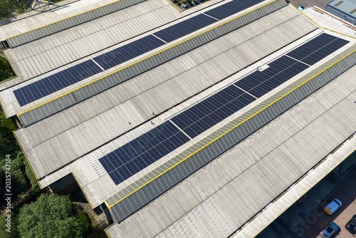 Aerial drone view of industrial warehouse rooftops covered with solar panels in Leeds West Yorkshire UK showing renewable energy infrastructure and geometric commercial building patterns from above