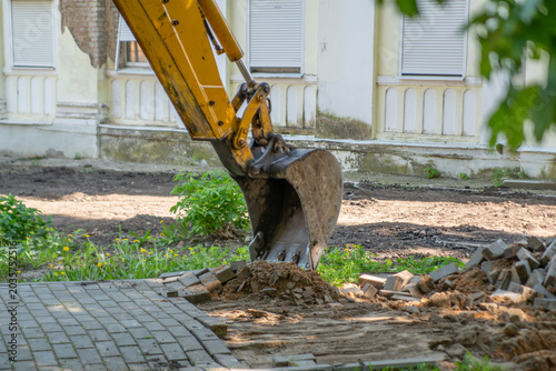 Bild auf Leinwand The photo captures the moment of construction or renovation work, where an excavator dismantles the paving stones on a busy street, creating the impression of progress and transformation