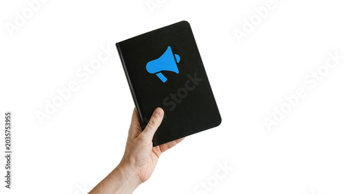 фотографія Isolated hand holding black notebook with blue megaphone icon, ideal for communi