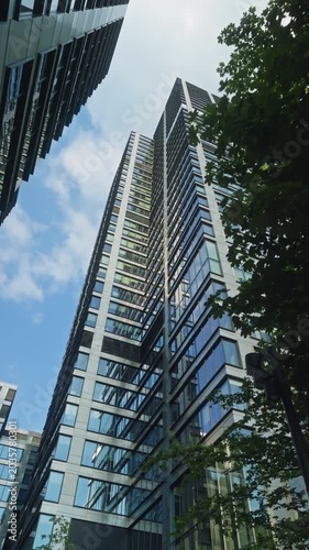 Wide angle dolly camera movement looking up modern office tower business buildings with blue sky reflections, skyscrapers in financial district, architecture and success concept