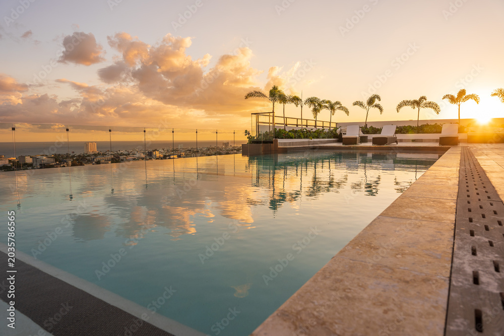 Fototapeta premium Luxury infinity pool reflecting a beautiful golden sunset in the Caribbean