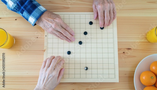 Seniors play board game on table.