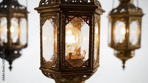 Ornate gold lanterns with intricate lattice metalwork hang in a softly lit antique interior
