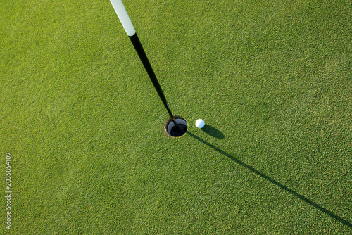 Looking down at golf ball next to green hole