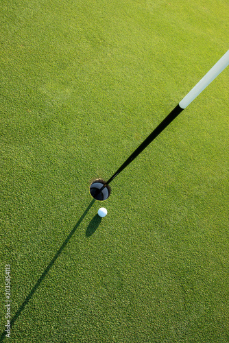 Looking down at golf ball next to green hole