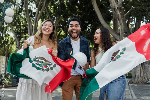 group of mexican soccer fans holding a soccer ball and national flag supporting to their sport team outdoors in Mexico city in Latin America