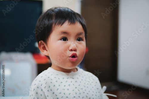 фотографія Portrait of a cute little Asian girl making a funny pouting expression at home