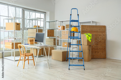 Foto Workplace, stepladder and shelf units with cardboard boxes in warehouse