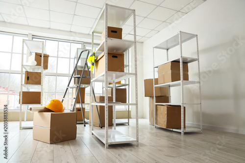 Schilderij op canvas Shelf units with cardboard boxes and stepladder in warehouse